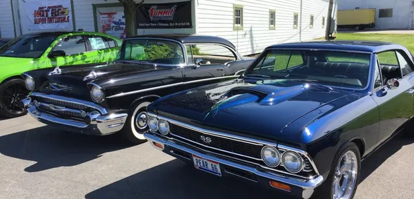 A 1957 Chevy and a 1966 Chevelle SS in front of the 30th Annual Hot Rod Super Nationals banner
